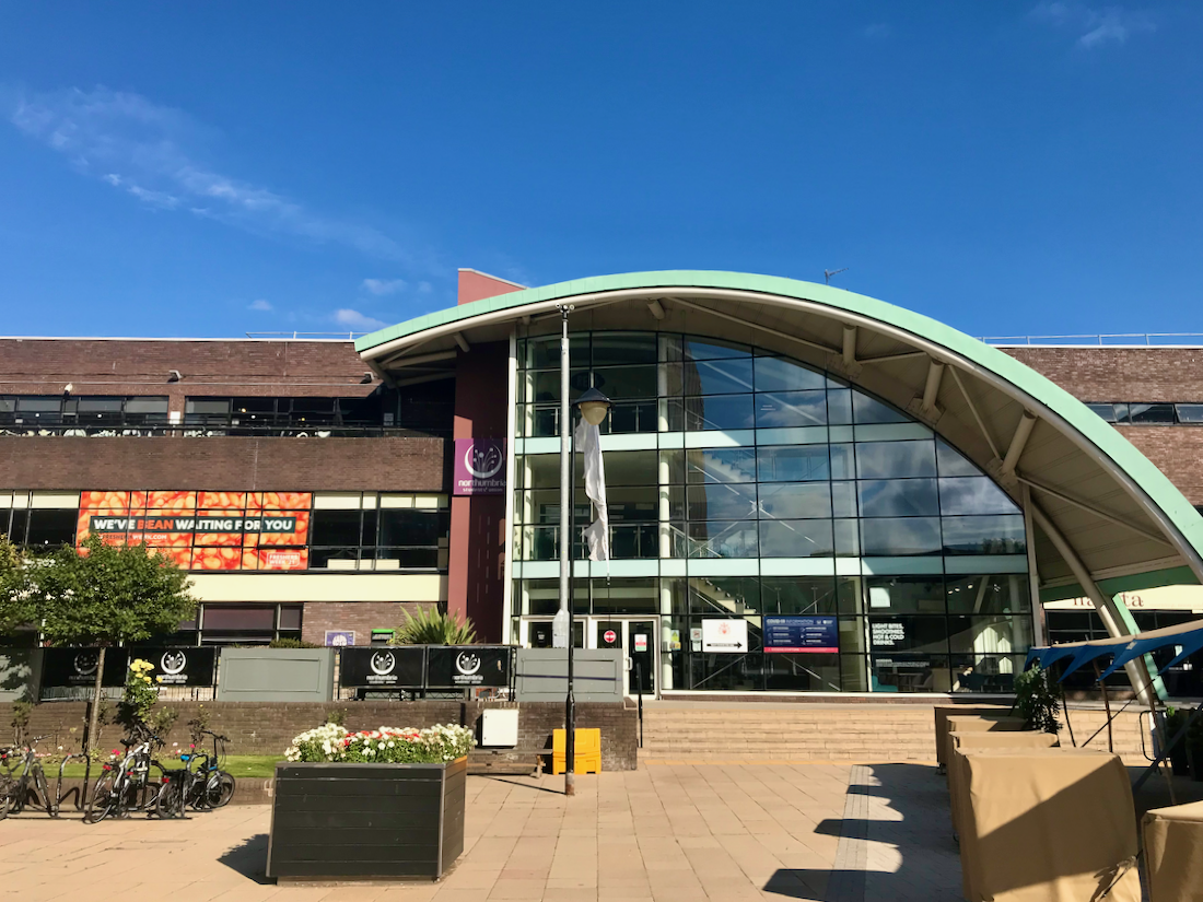 Northumbria student union building on a sunny day. A glass and metal building with a tall curved design