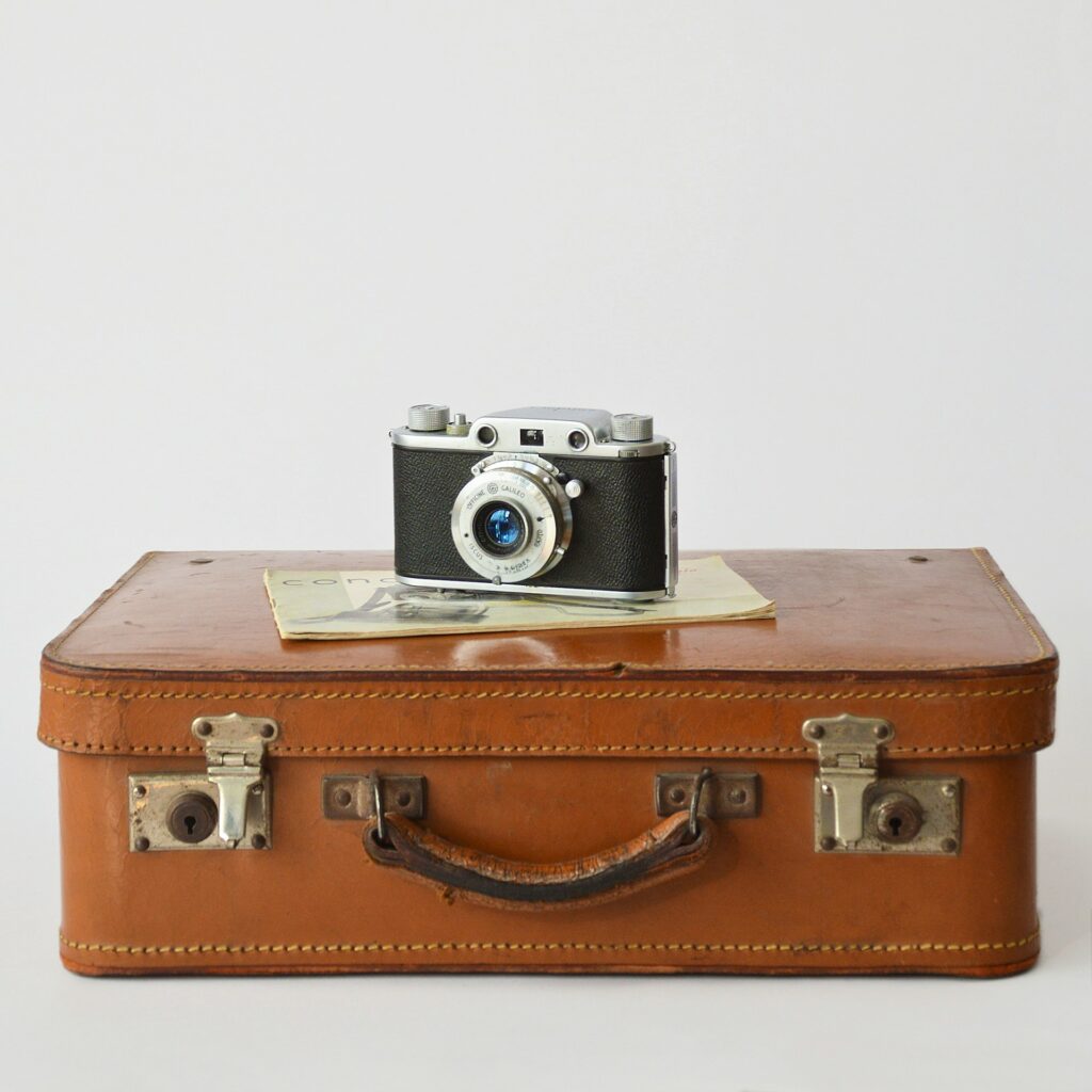 Vintage brown leather suitcase with an old camera sitting on top